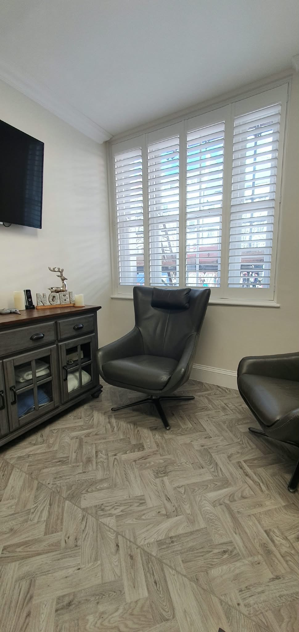 Modern living room with black leather chair — Sustainable Shutters & Blinds