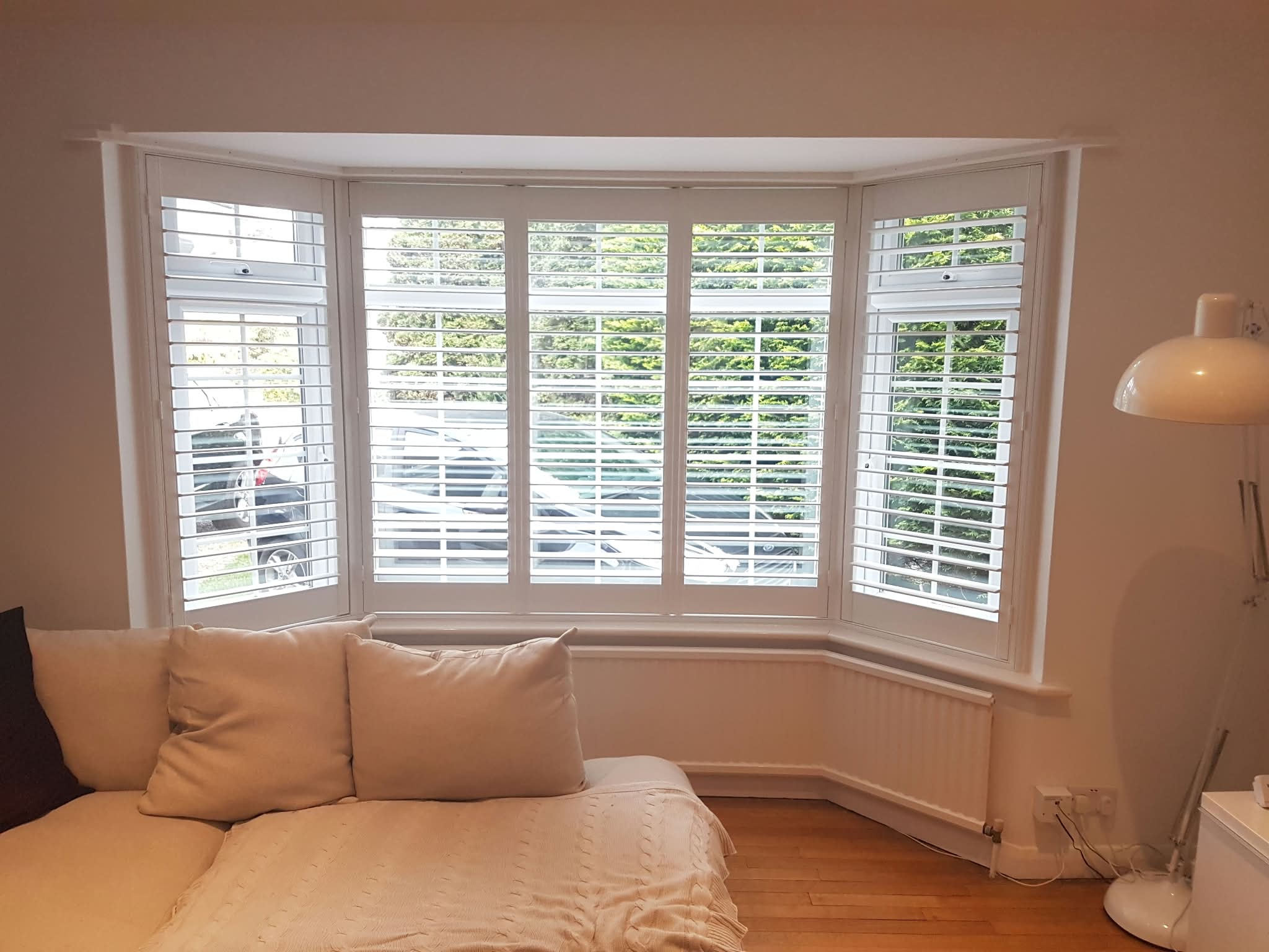 Shutters in a bay window bedroom — Sustainable Shutters & Blinds