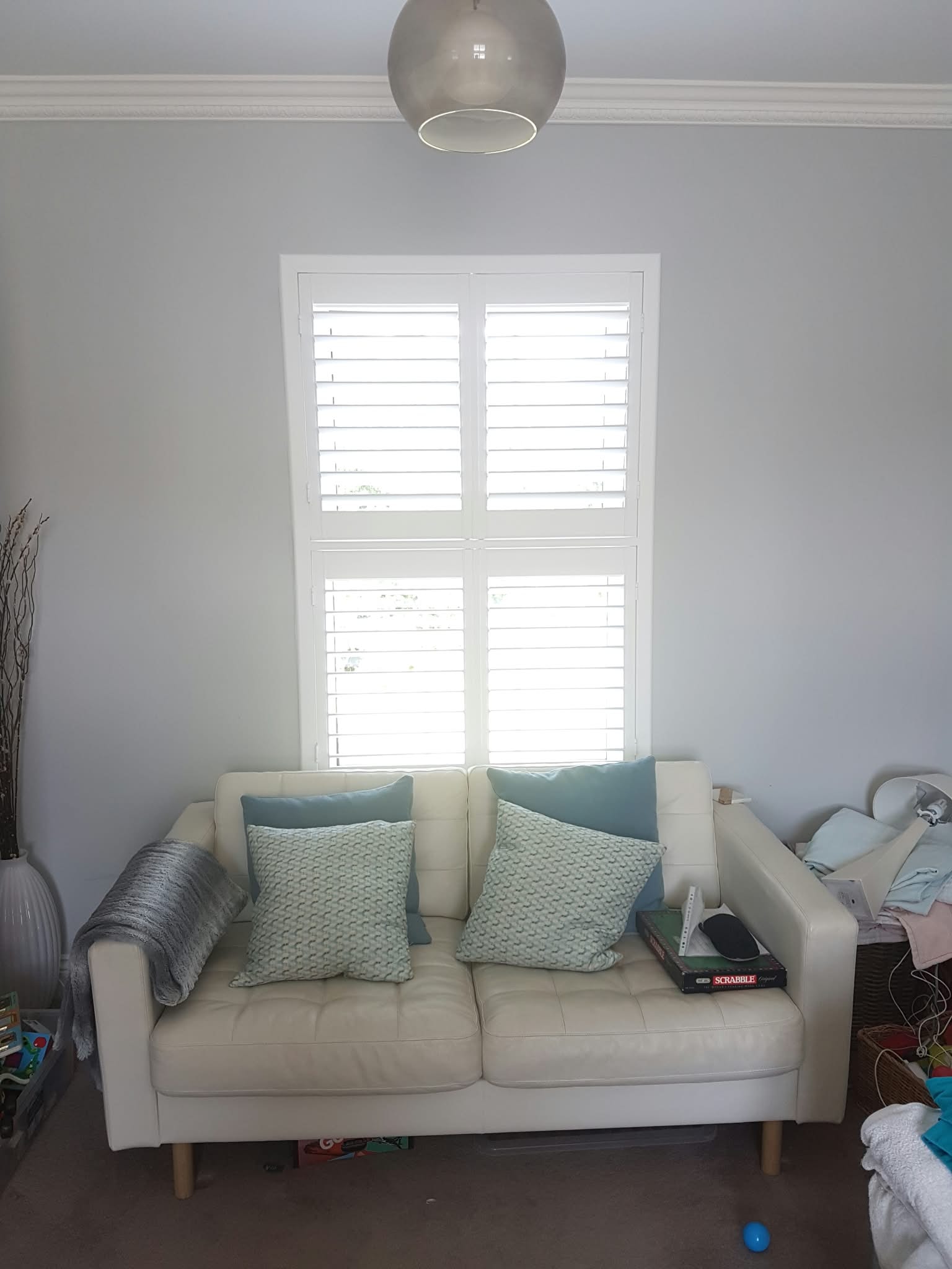 Shutters above a cream sofa — Sustainable Shutters & Blinds
