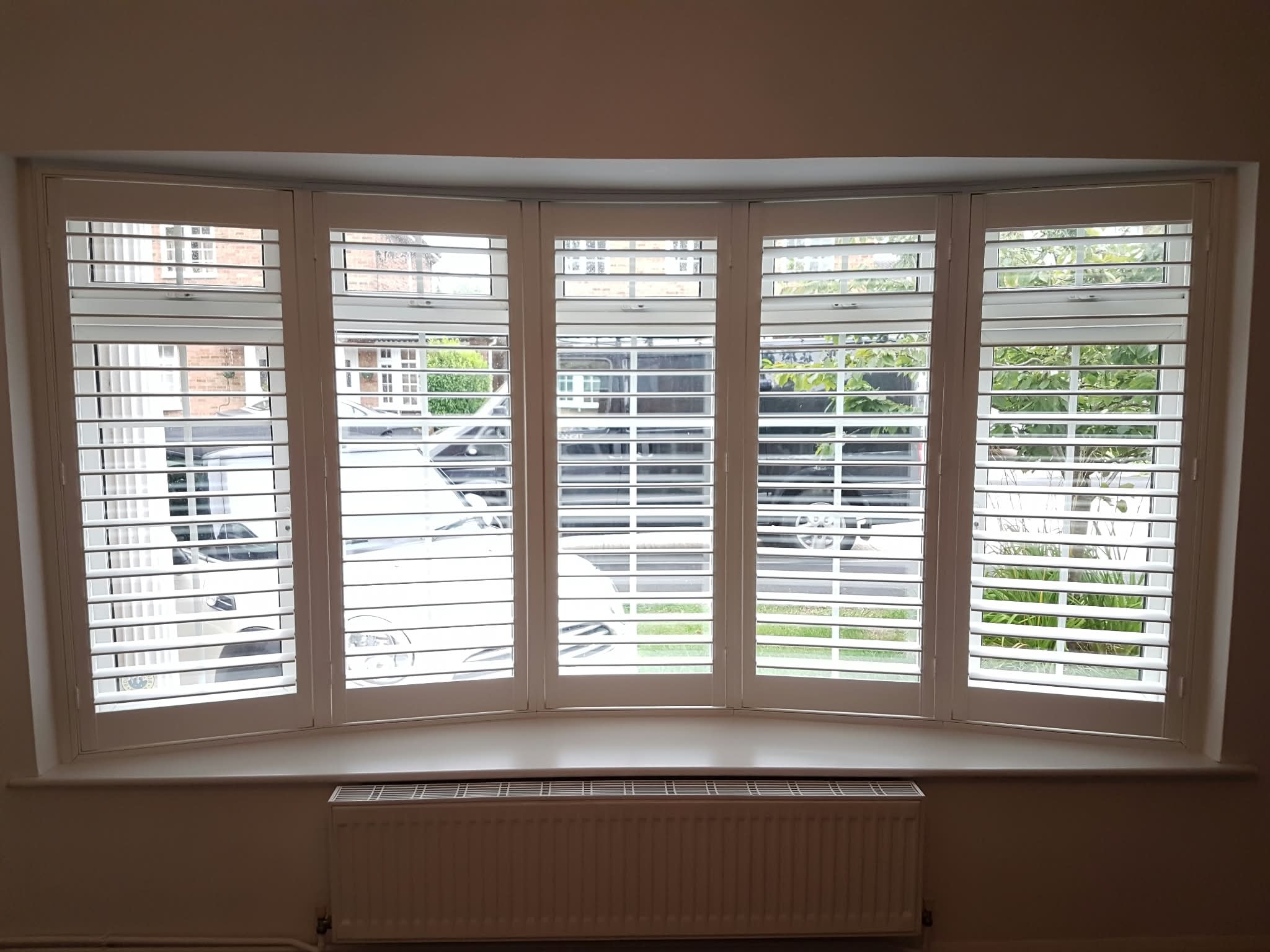 White plantation shutters on a bay window — Sustainable Shutters & Blinds