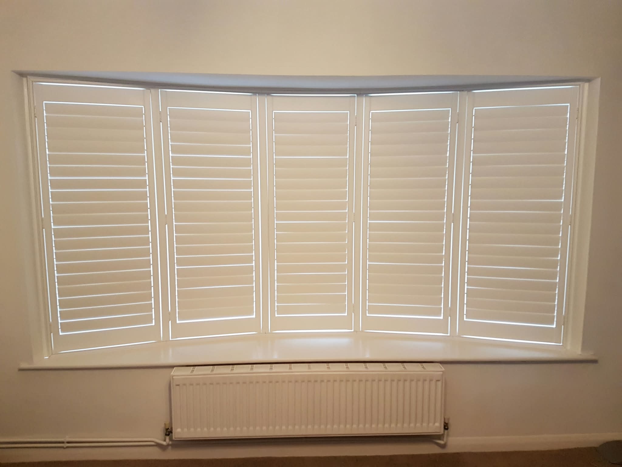Five-panel white shutters on a window — Sustainable Shutters & Blinds