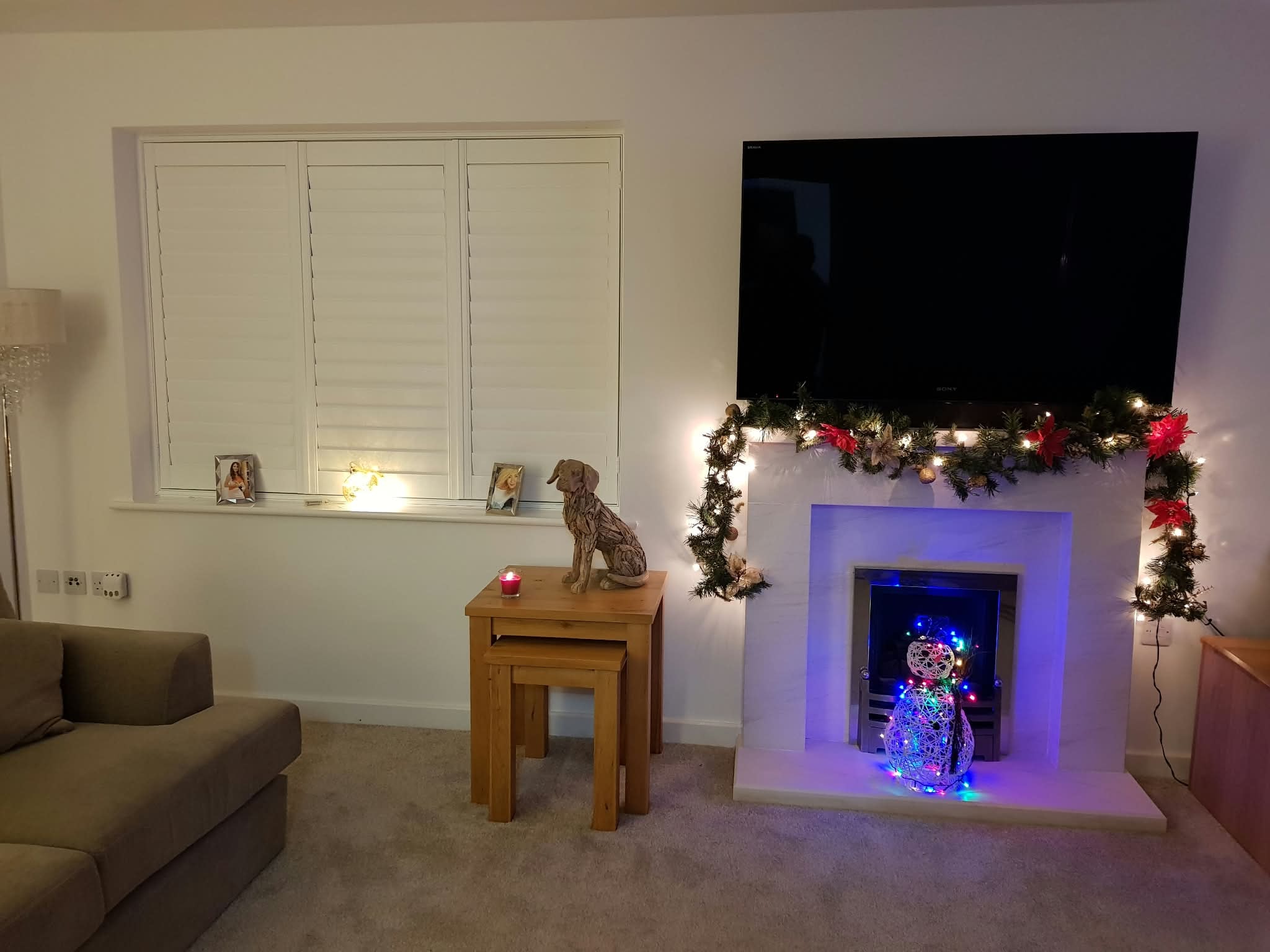 White shutters in a living room with Christmas fireplace — Sustainable Shutters & Blinds