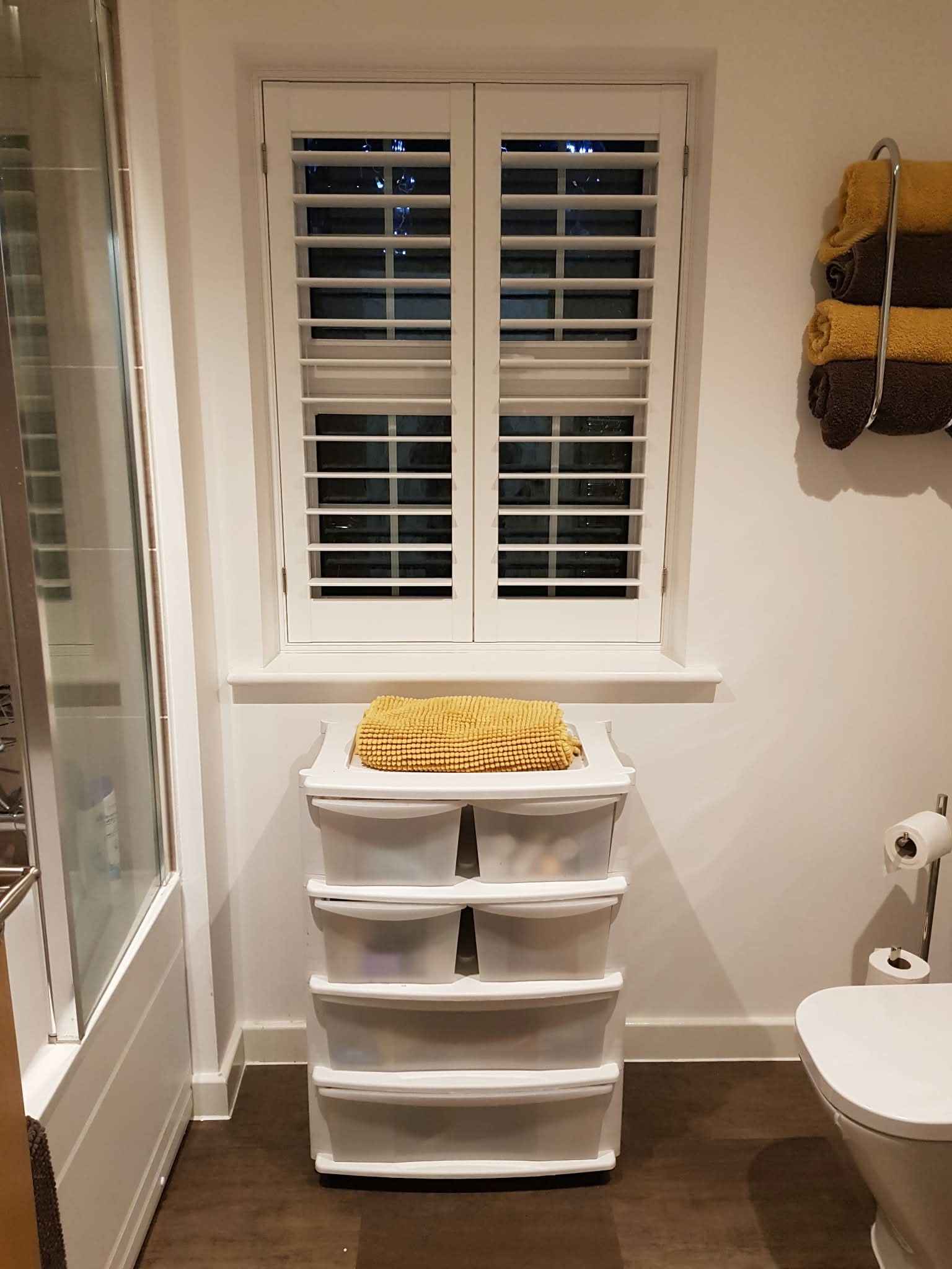 White shutters in a bathroom at night — Sustainable Shutters & Blinds