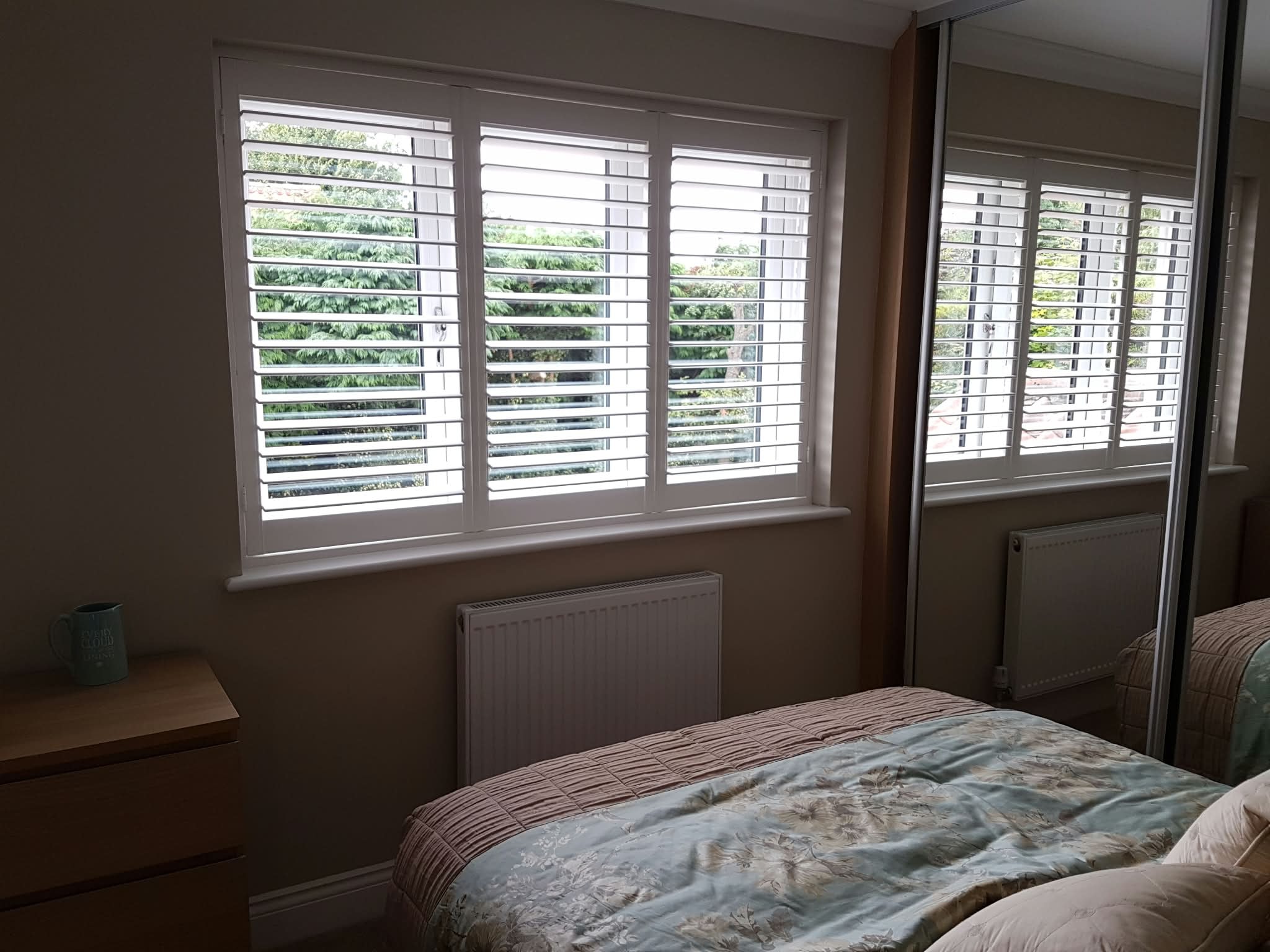 White shutters in a bedroom with open louvres — Sustainable Shutters & Blinds
