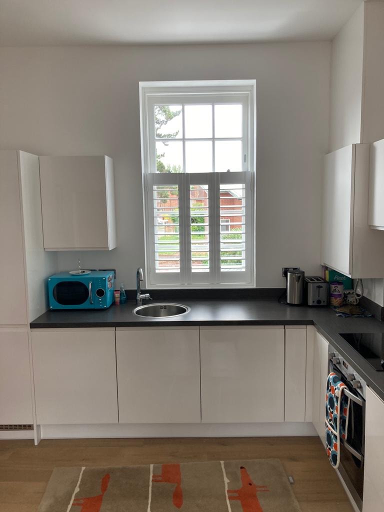 Shutters in a kitchen with blue microwave — Sustainable Shutters & Blinds