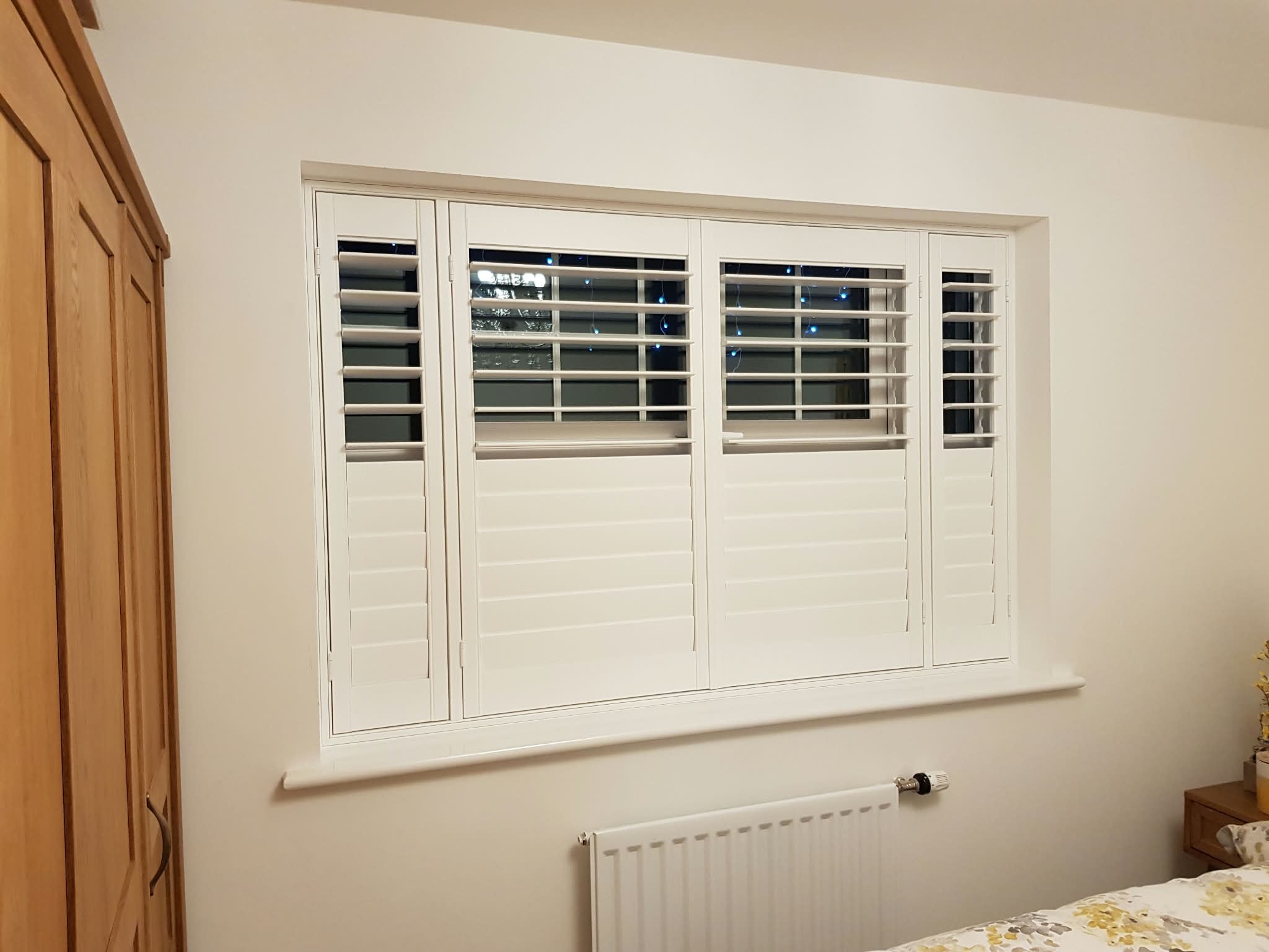 White plantation shutters on a bedroom window — Sustainable Shutters & Blinds