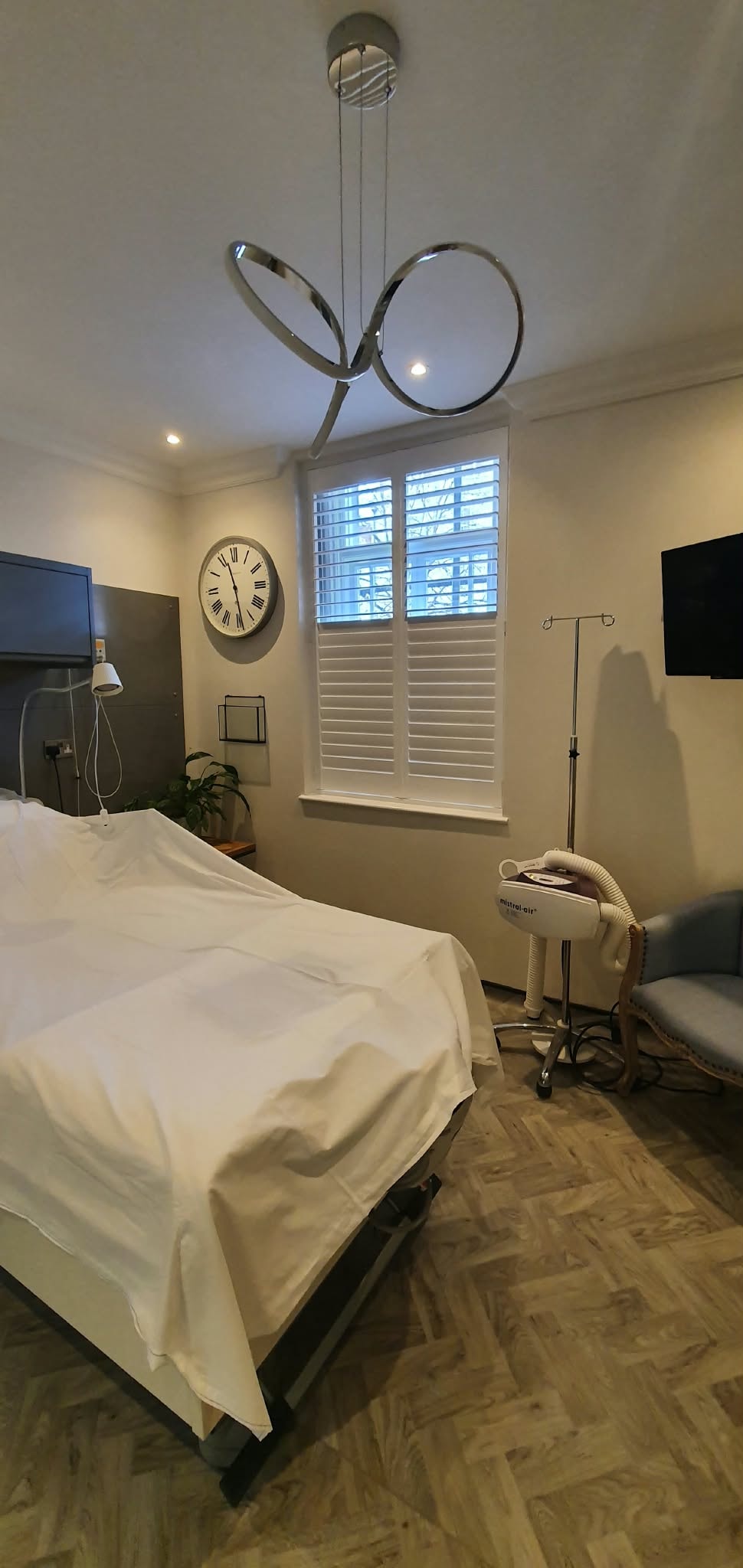 White shutters in a living room with leather chair — Sustainable Shutters & Blinds