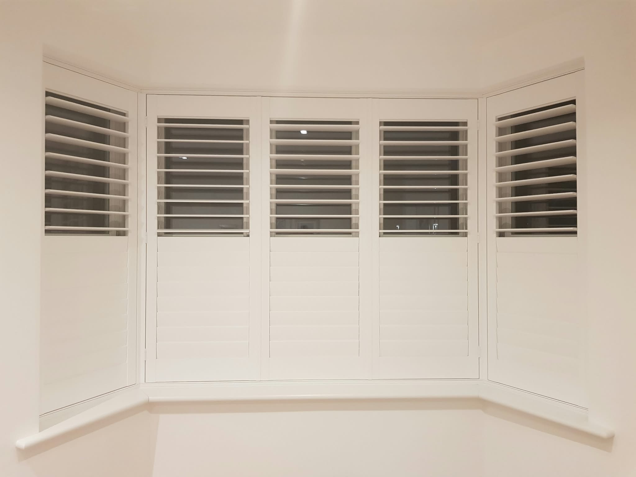 White shuttered bay window interior — Sustainable Shutters & Blinds