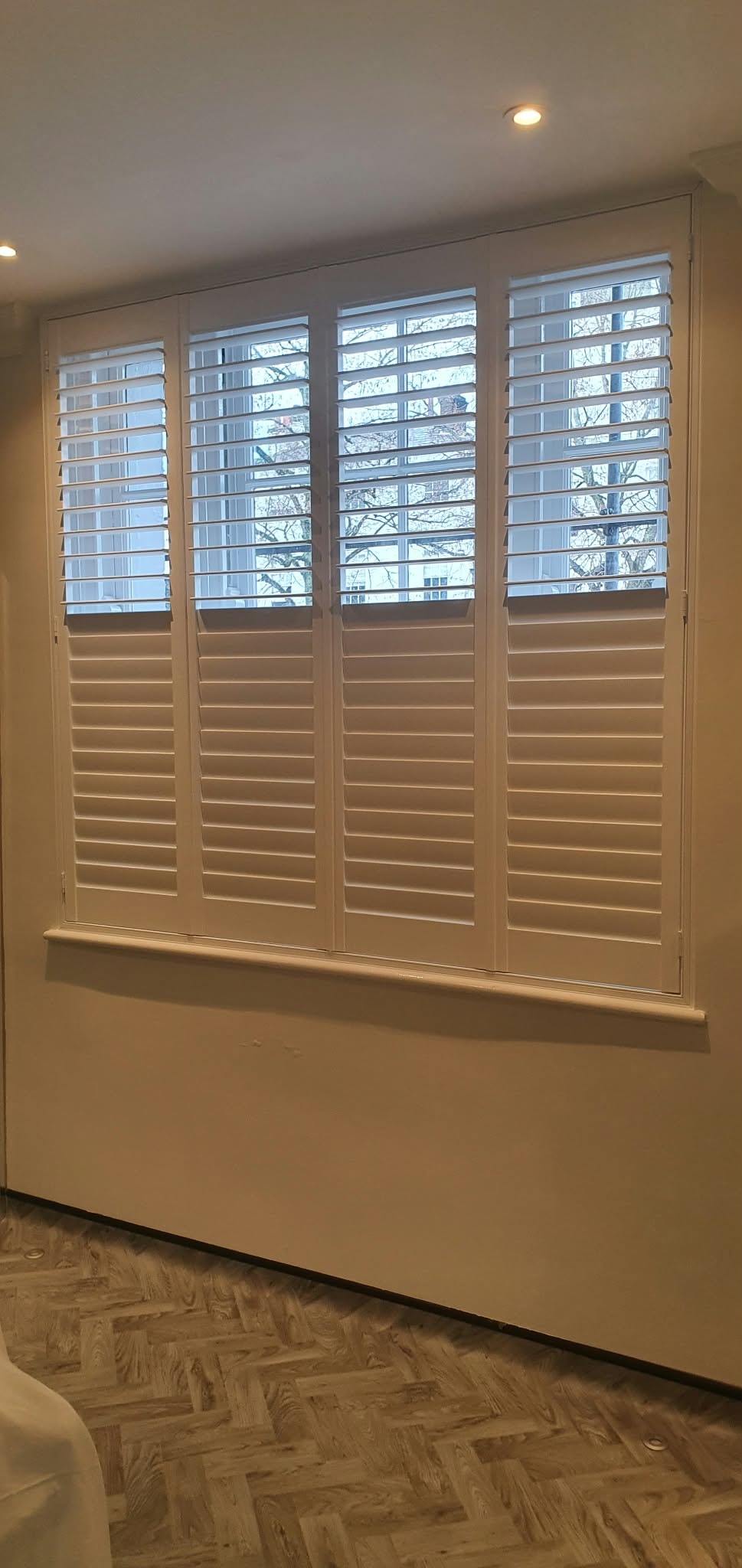 Full-height white shutters on a large window — Sustainable Shutters & Blinds