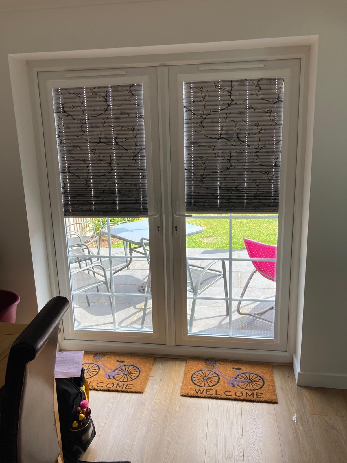 Patterned pleated blinds on French doors with garden view — Sustainable Shutters & Blinds