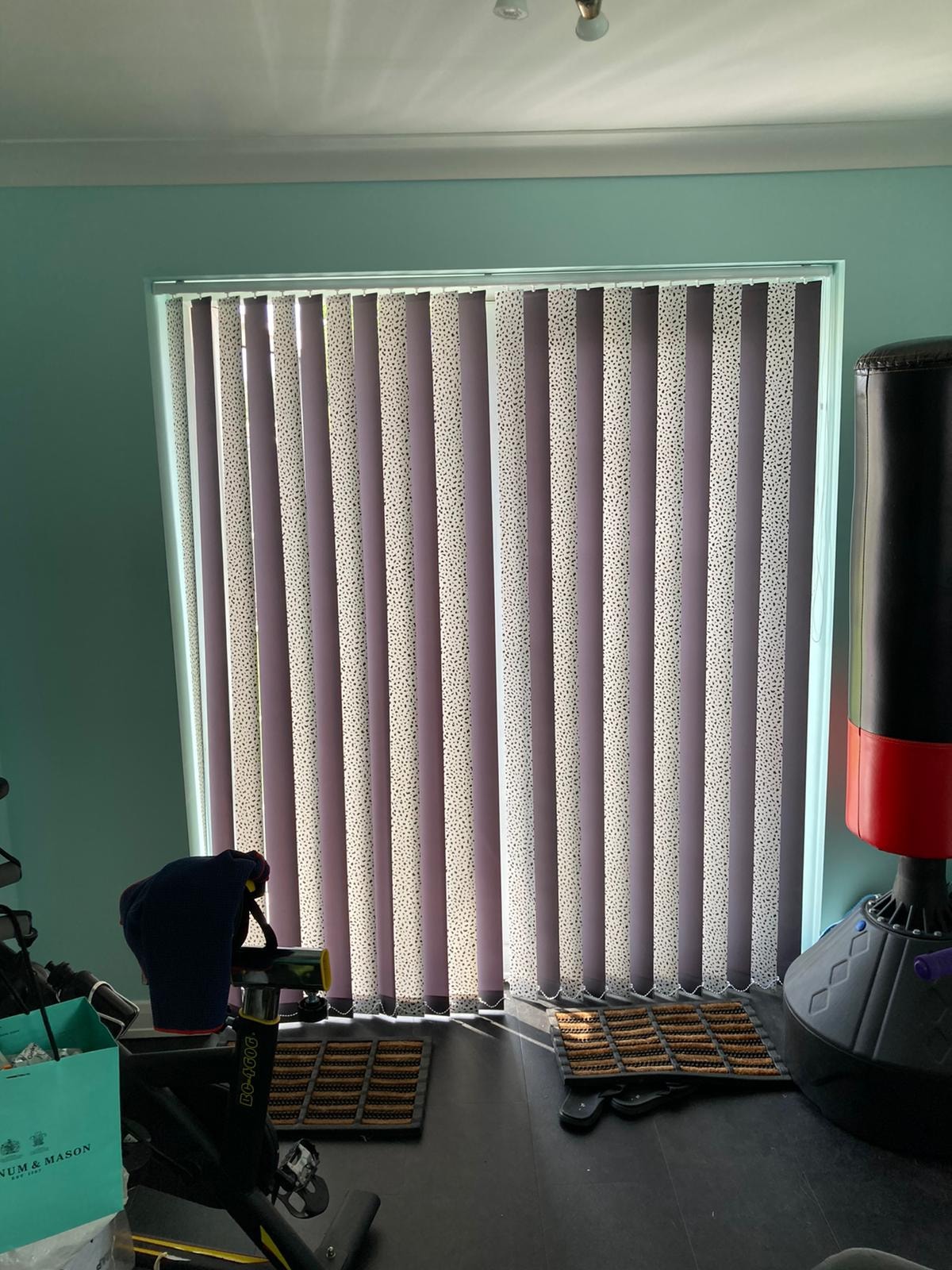 Patterned vertical blinds in a teal-walled room — Sustainable Shutters & Blinds