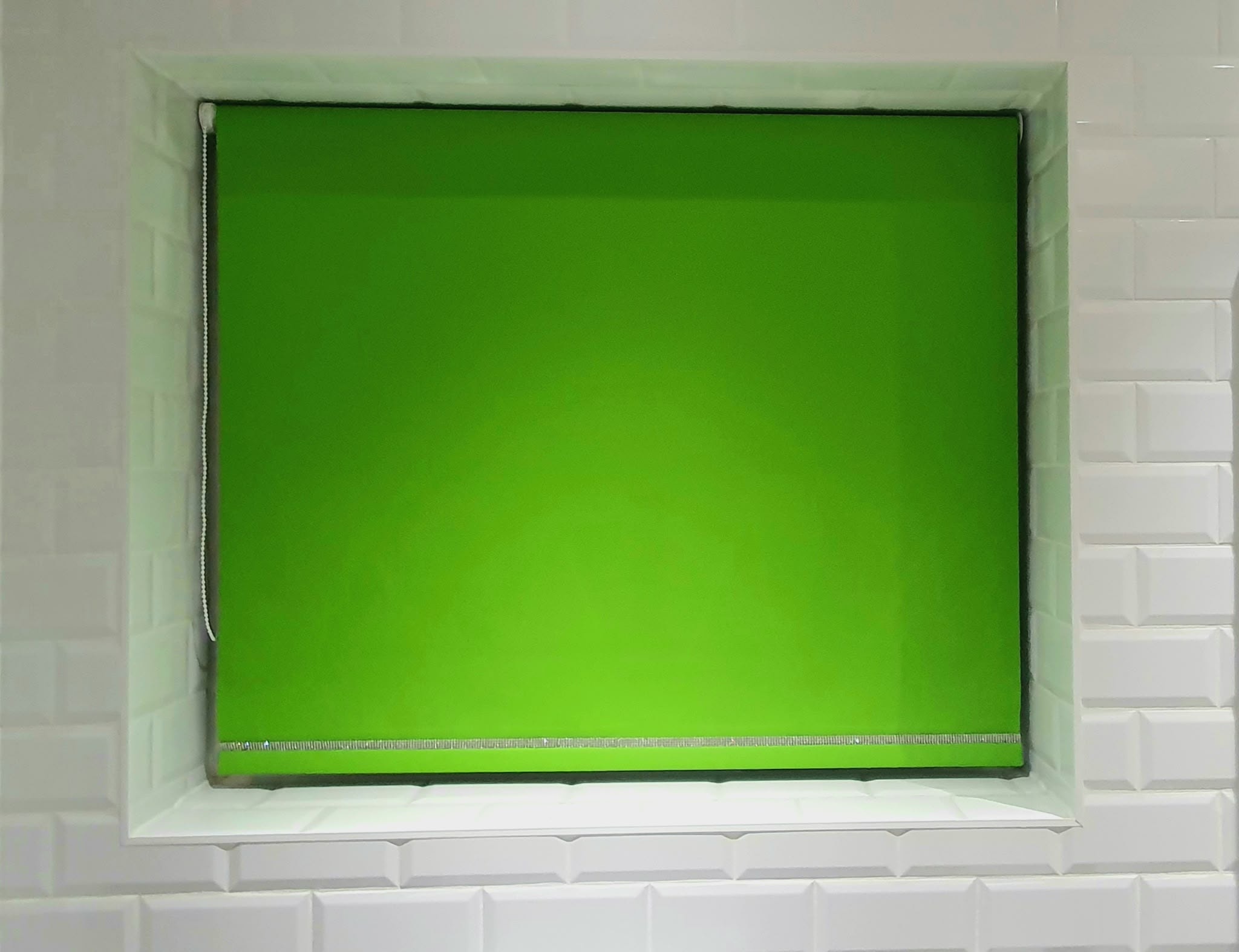 Bright green roller blind in a white-tiled bathroom — Sustainable Shutters & Blinds