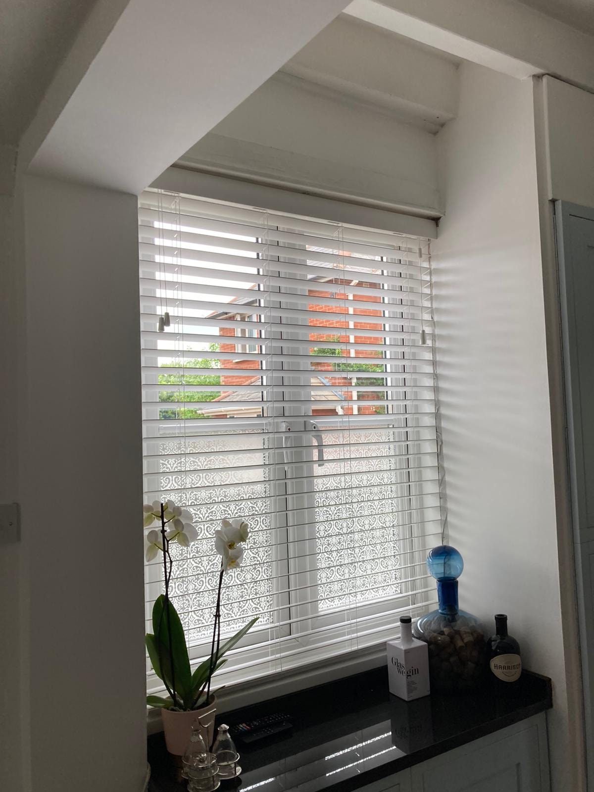 White Venetian blind in a kitchen with orchid on worktop — Sustainable Shutters & Blinds
