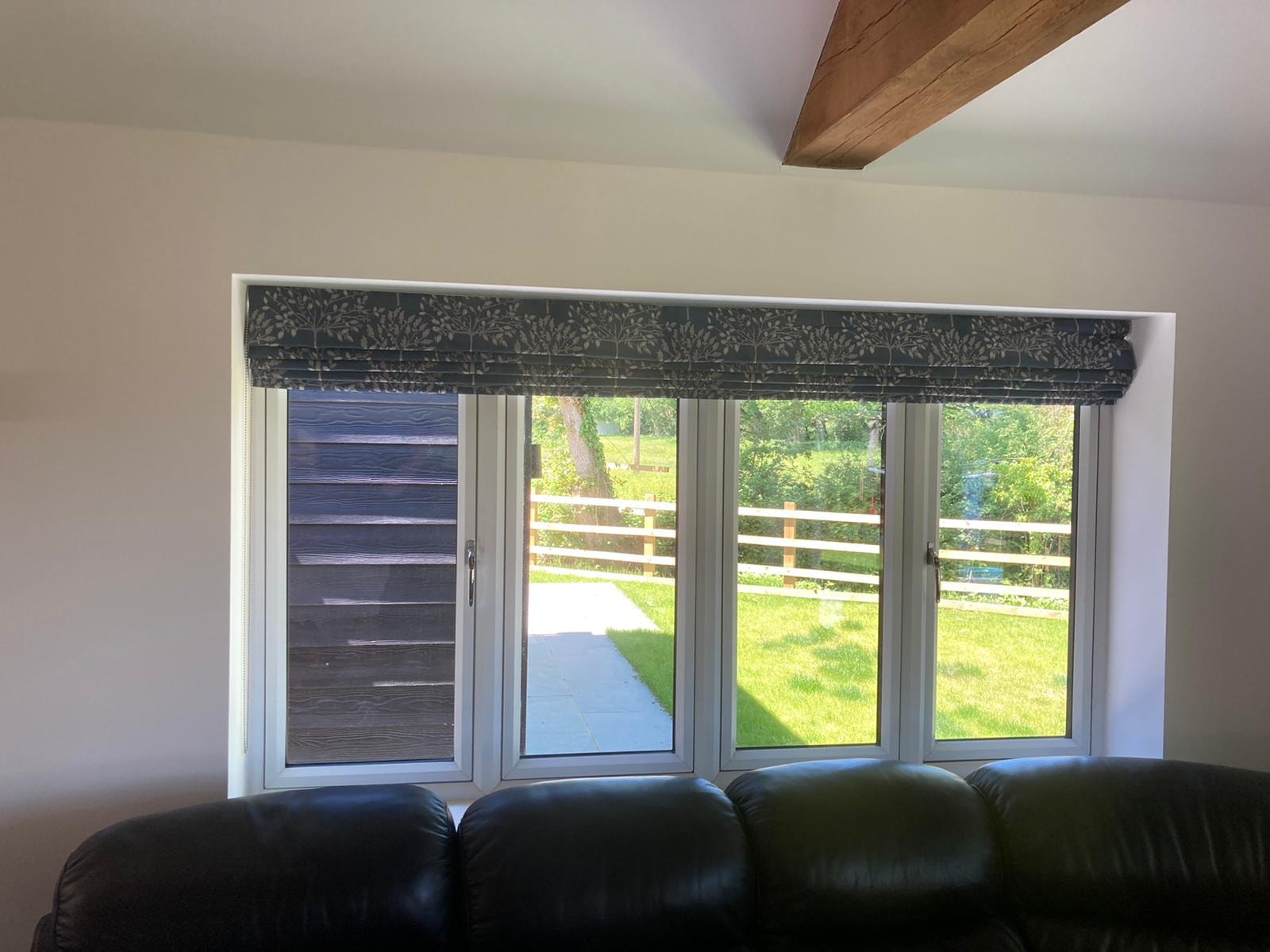 Dark Roman blind with leaf pattern on a wide window with vaulted ceiling — Sustainable Shutters & Blinds