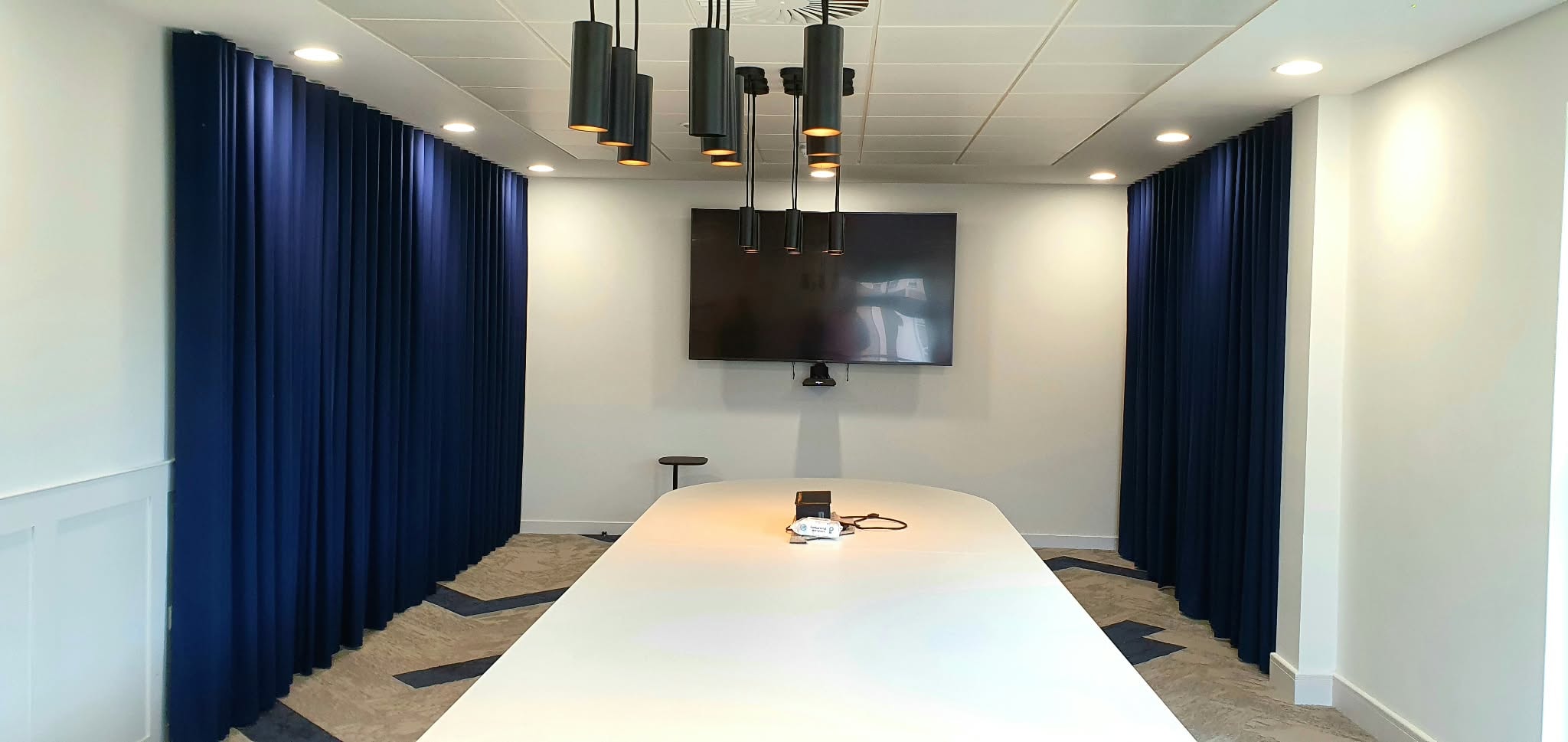 Navy wave curtains in a boardroom with pendant lighting — Sustainable Shutters & Blinds