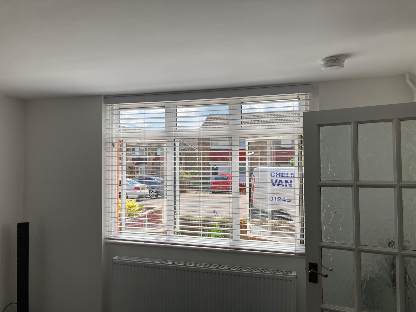 White Venetian blinds on a wide window with garden view — Sustainable Shutters & Blinds