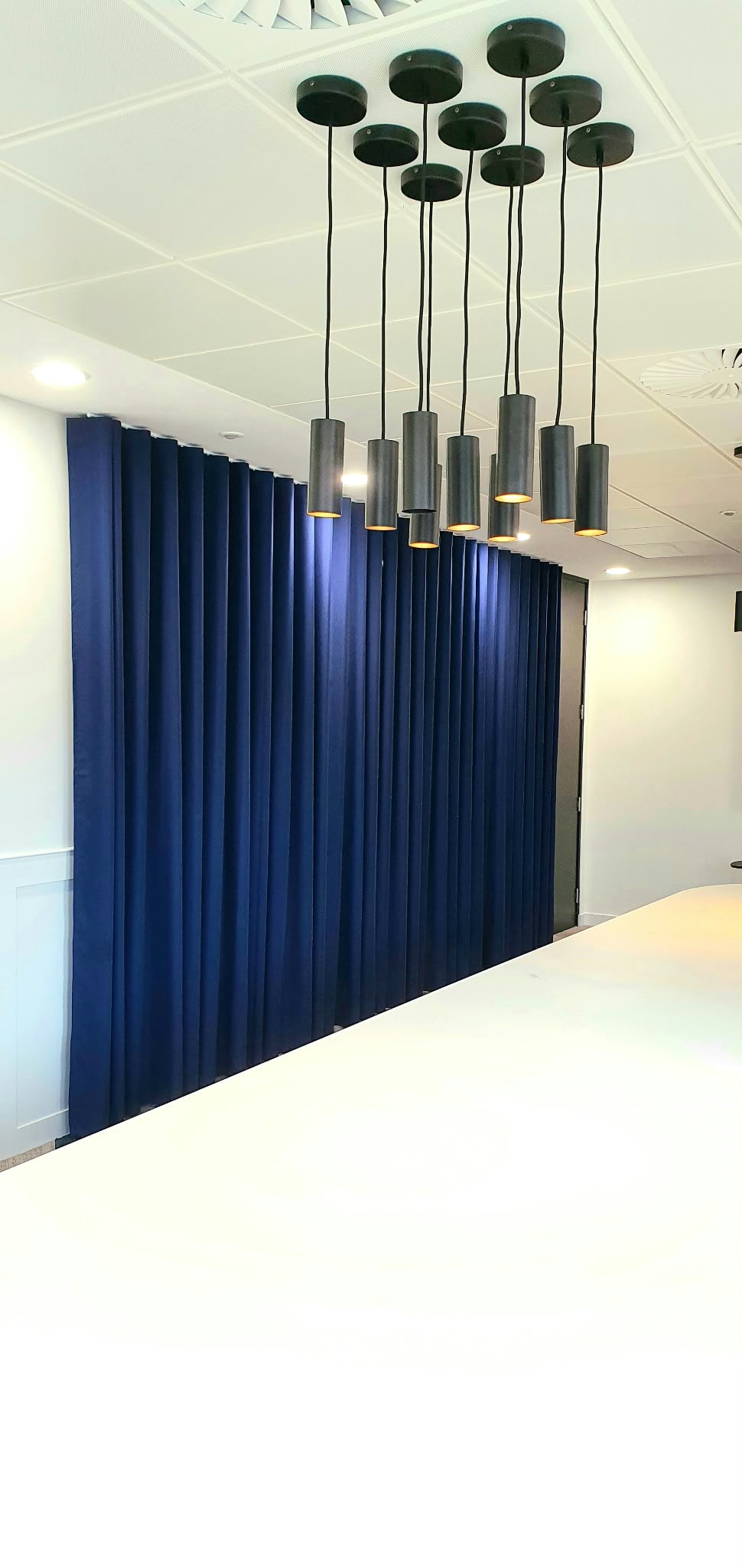 Modern pendant lights above blue curtains — Sustainable Shutters & Blinds