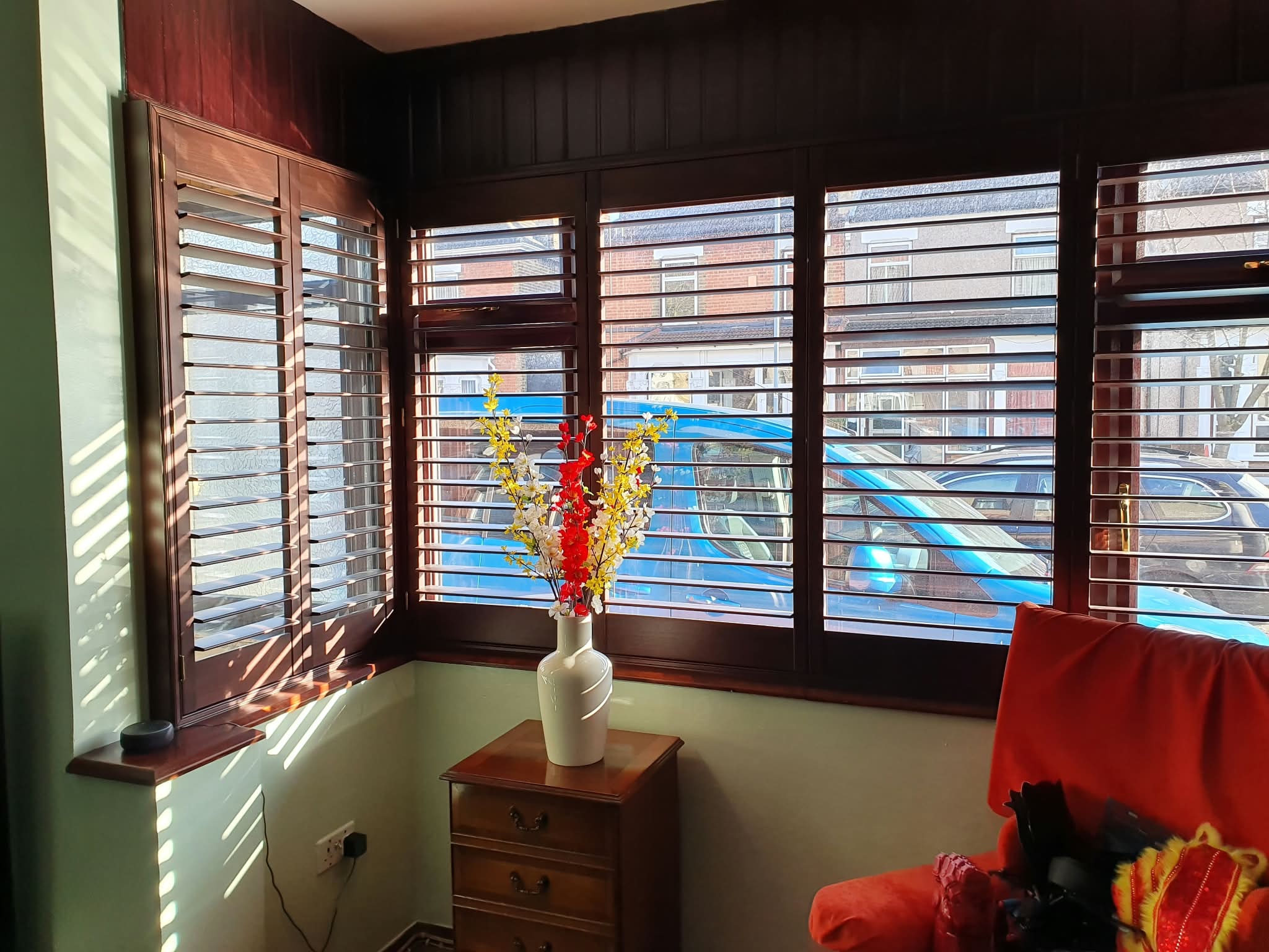 Shutters in a living room with flowers — Sustainable Shutters & Blinds